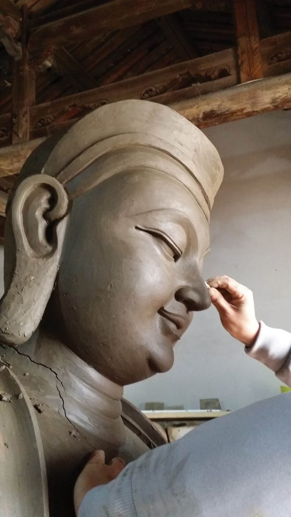 An artist makes adjustments to a clay model for a statue commissioned by H.E. Tsem Rinpoche.