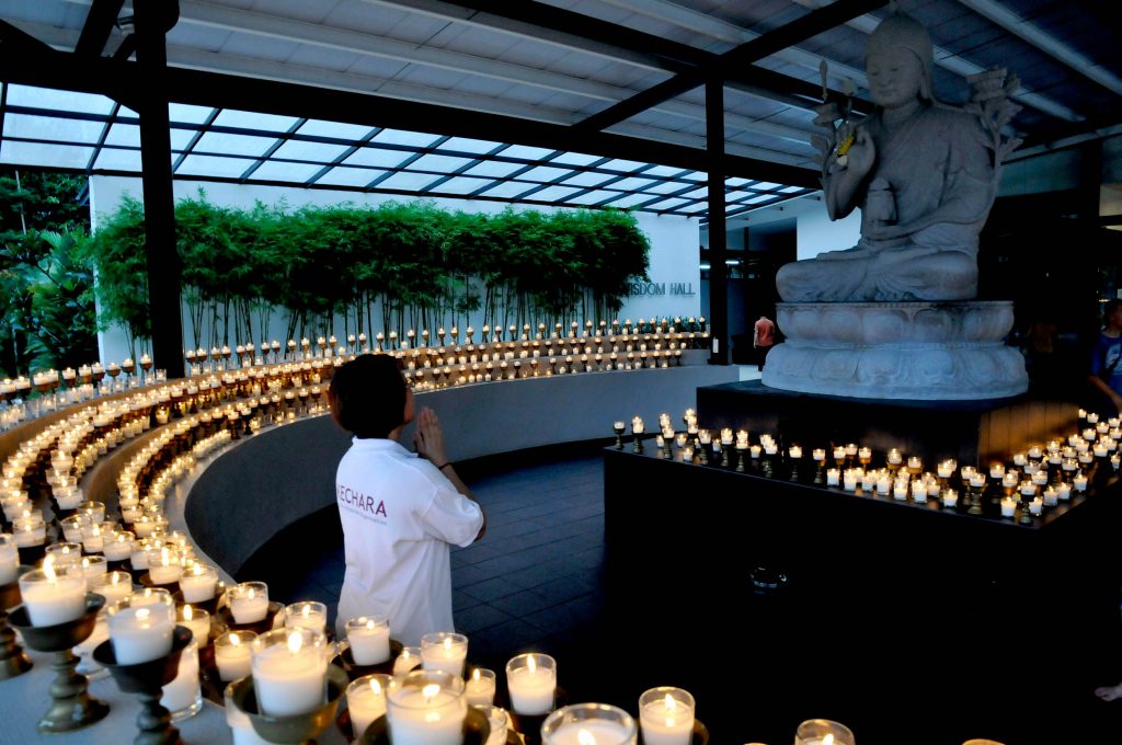 A devotee makes dedication prayers at Lama Tsongkhapa's shrine at the entrance of Wisdom Hall, Kechara Forest Retreat.